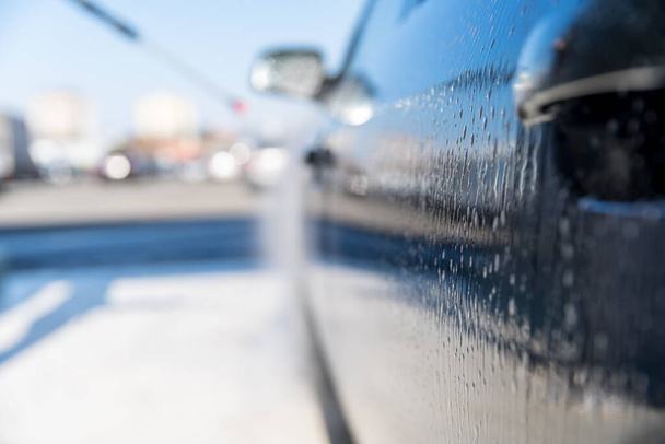 enjuague y aplicación de cera en la carrocería del automóvil mediante agua tratada a presión en una estación de autoservicio
 - Foto, imagen