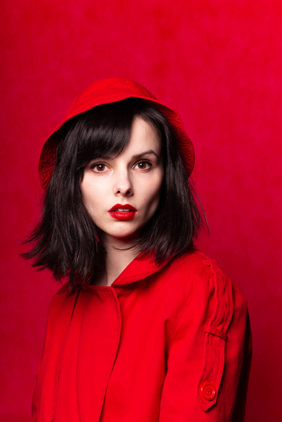 girl in red panama, red lipstick, red trench coat, red background - Valokuva, kuva