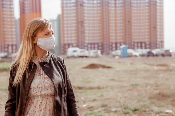 дівчина в медичній масці на тлі висотних будівель
 - Фото, зображення