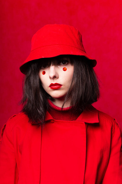 a woman with a bob haircut, wearing a red trench coat - Fotó, kép