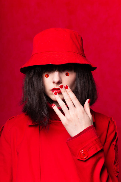 a woman with a bob haircut, wearing a red trench coat - Foto, Imagen