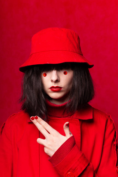 girl with red circles under the eyes, red background, red color - Photo, Image