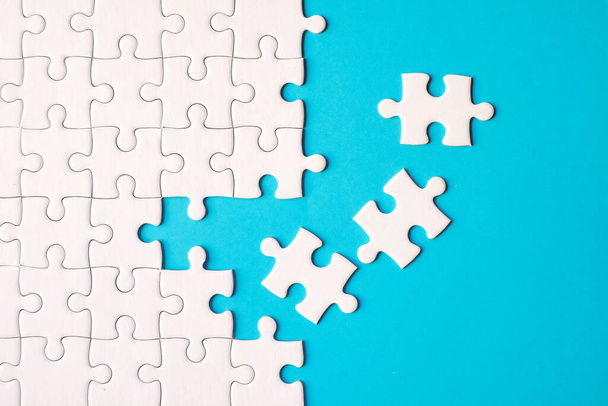 Many white jigsaw puzzle on blue background - idea solution concept. - Photo, Image