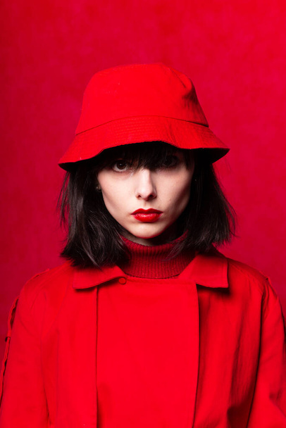 girl in a red trench coat on a red background - Foto, afbeelding