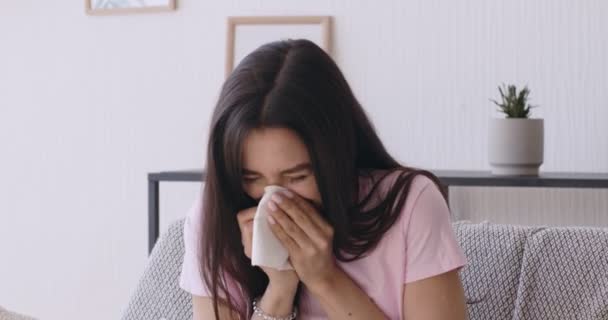 Młoda kobieta dmucha nos w domowe wnętrze - Materiał filmowy, wideo