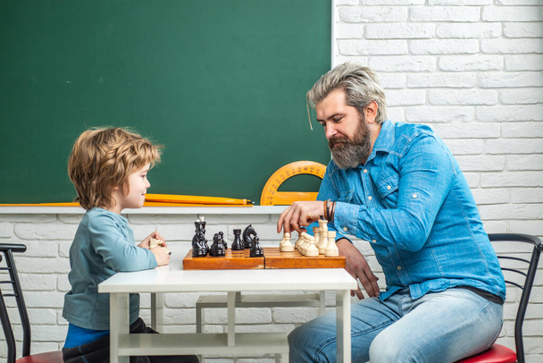 父は息子にチェスを教える。チェス戦略。チェスの成功と勝利。教育と人々の概念。幸せな父の日. - 写真・画像