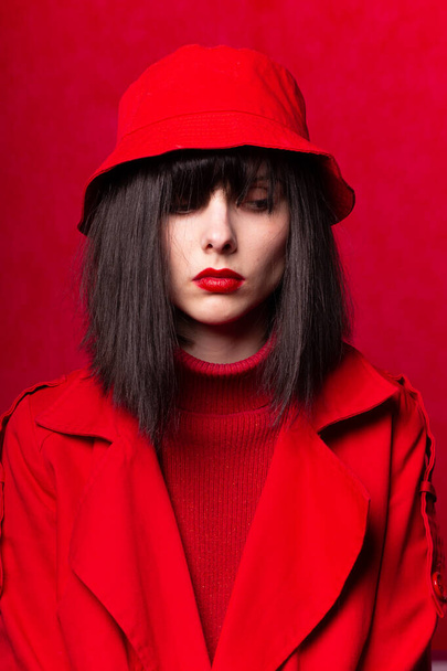 girl in a red sweater and red cloak, red background - 写真・画像