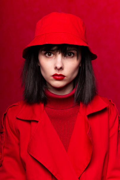girl in a red sweater and red cloak, red background - Фото, зображення