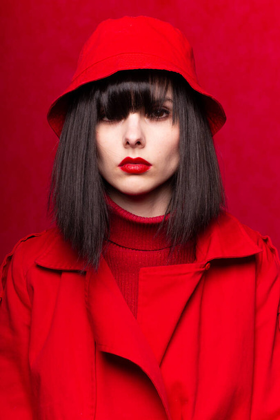 woman with bangs in red clothes, red background - Foto, Imagen