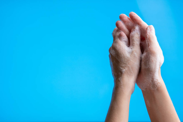 Ręce myjące ręce za pomocą pianki mydlanej na niebieskim tle, zbliżenie strzał. Zapobieganie zagrożeniom19, bakterie, koncepcja opieki zdrowotnej. - Zdjęcie, obraz