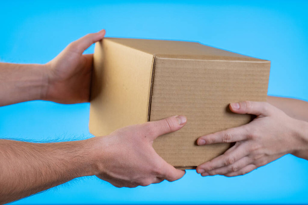 Two hands taking a box gift on blue background - Foto, Bild