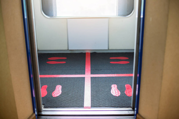 Вибіркове фокусування на підлозі пасажирського підйомника з позначкою для соціального дистанціювання, щоб уникнути поширення коронавірусу (Ковід-19). Поняття відстані або відстані. Ідеї про спалах COVID-19. - Фото, зображення