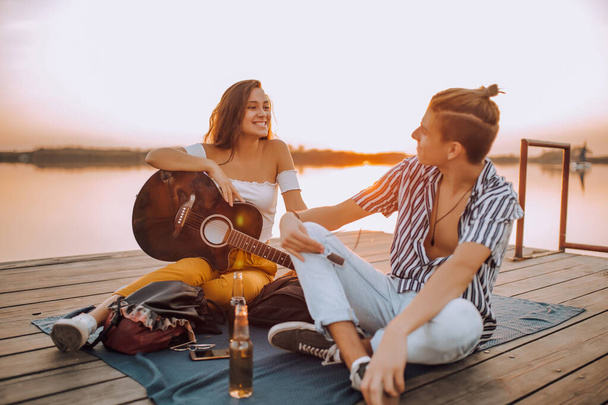 Happy young cheerful couple in love having a romantic date by the river - Photo, image