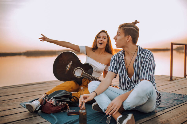 Feliz joven alegre pareja enamorada divirtiéndose junto al río. Chica mostrando algo interesante a su novio
. - Foto, imagen