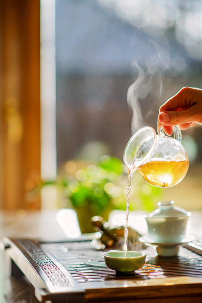 Processo di preparazione del tè, cerimonia del tè, una tazza di tè oolong verde appena preparato, luce morbida calda. Concentrazione morbida. - Foto, immagini