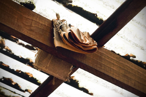 Старая ветхая коричневая газета висит на деревянной балке возле крыши
 - Фото, изображение