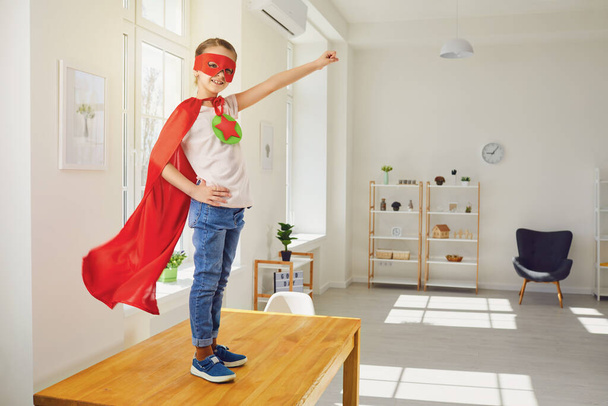 Child super hero.Kid smiling playing a superhero having fun in a room with a window. - Фото, изображение