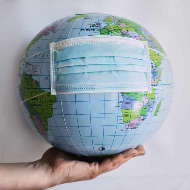 Globe on hand with respiratory mask - Covid 19 - Photo, Image