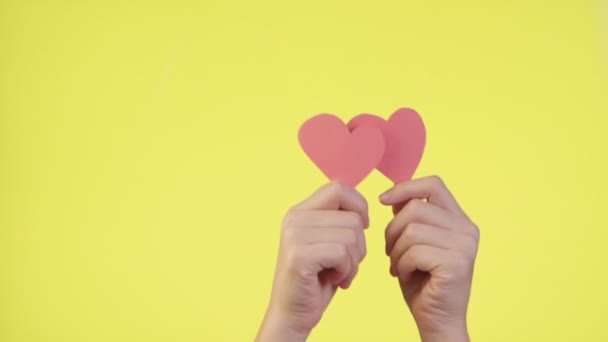 Female hold in hands little red hearts isolated on yellow background. Social network tenderness concept. Valentines day international women - Footage, Video