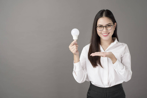 Beautiful intelligent woman is holding light bulb in studio  - Φωτογραφία, εικόνα
