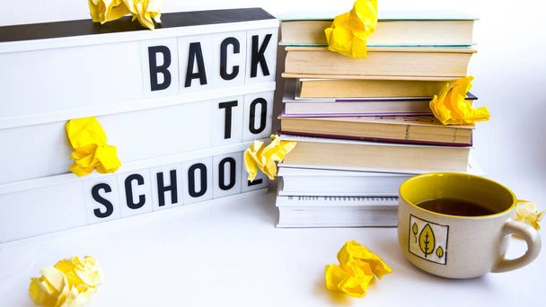 Lightbox with BACK TO SCHOOL text and books on white background, Stack of old book education concept background, many books piles with copy space for text crumpled yellow paper
 - Фото, изображение