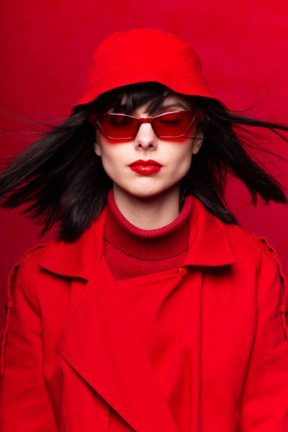 vrouw in rood bril op een rode achtergrond - Foto, afbeelding