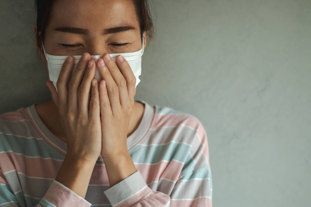 Beautiful Asian woman infected with the Coronavirus (COVID-19) sneezing in medical hygiene protective mask. Health care, quarantine and prevent from risk of Coronavirus (COVID-19) concept. - 写真・画像