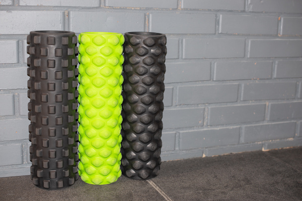 three foam rollers standing near the grey bricked wall - Фото, изображение