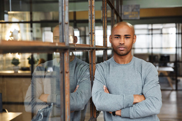 Image of young attractive bald african american man standing with arms crossed while working in office - Valokuva, kuva