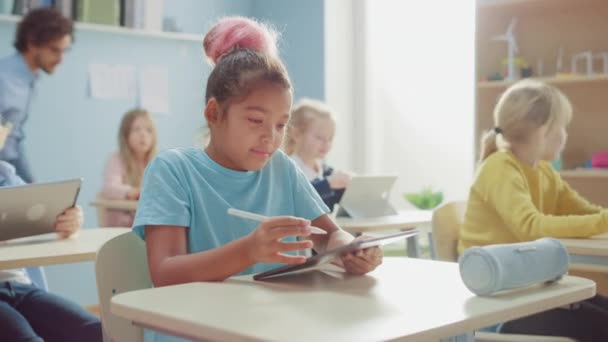 Szkoła Podstawowa Informatyka Klasa: Słodka Dziewczyna Używa Cyfrowego Tabletu Komputer, Jej Koledzy Pracowali Z Laptopami Również. Dzieci coraz nowoczesnej edukacji w STEM, gry i uczenia się - Materiał filmowy, wideo