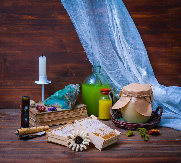 Εργαστήριο ενός αρχαίου αλχημιστή με μέλι, βότανα, ένα βιβλίο και ένα κερί σε ξύλινο φόντο σε ρετρό στυλ - Φωτογραφία, εικόνα