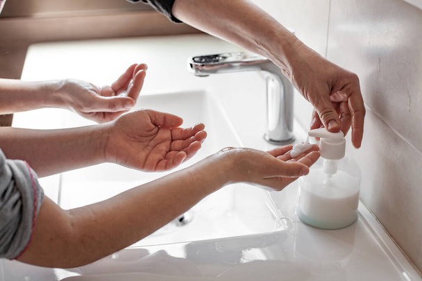 Äiti opettaa tyttärelleen, miten pestä kätensä kunnolla saippualla koronavirusinfektion estämiseksi
 - Valokuva, kuva