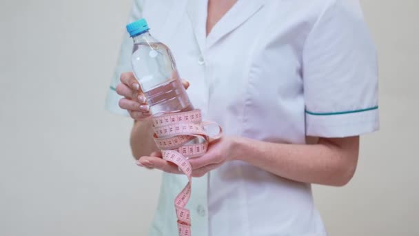 concepto de estilo de vida saludable médico nutricionista - la celebración de botella de agua y cinta métrica
 - Metraje, vídeo