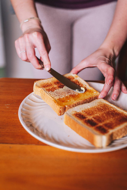 two hands spreading butter on toast - Fotó, kép