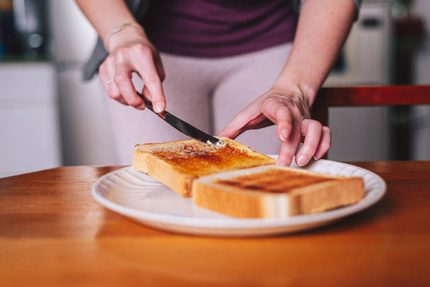 two hands spreading butter on toast - Fotoğraf, Görsel