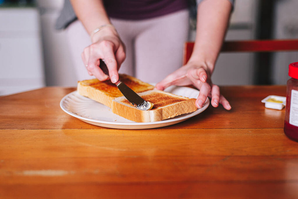 two hands spreading butter on toast - Foto, imagen