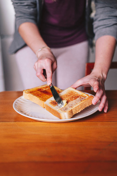 two hands spreading butter on toast - Photo, image