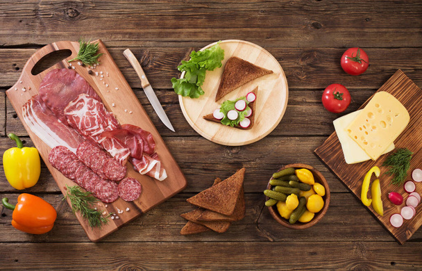 making sandwiches with meat and sausage on wooden table - Foto, Imagen