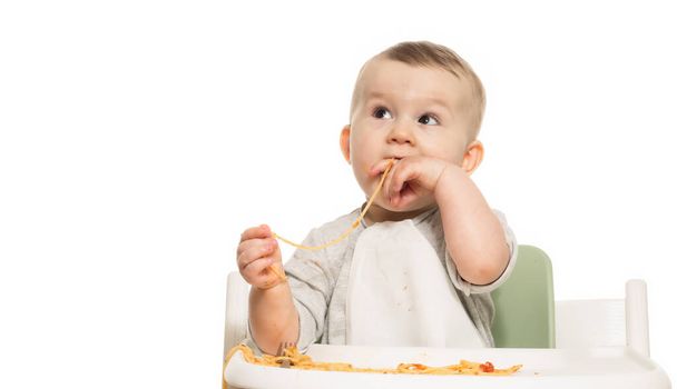 Portret zabawnego chłopca, który je spaghetti w sosie pomidorowym na białym, izolowanym tle.  - Zdjęcie, obraz