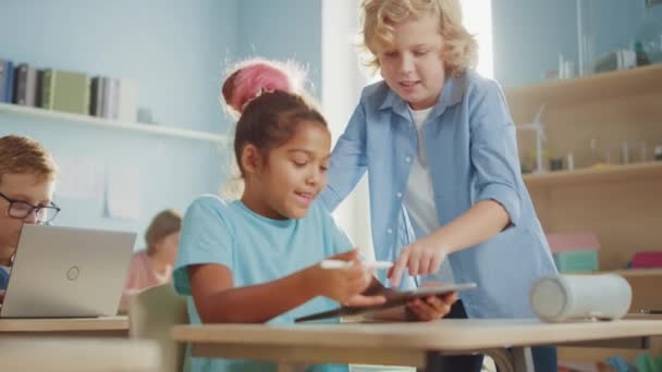 Elementary School Computer Science Class: Smart Girl Uses Digital Tablet Computer, Her Classmate Helps Her with the assignment. Children Getting Modern Education - Filmagem, Vídeo