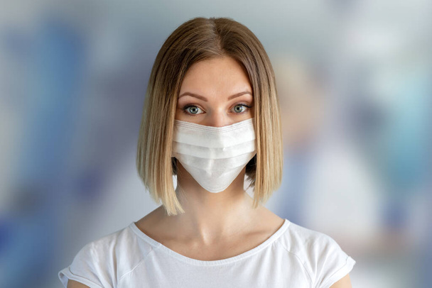 Νοσοκόμα ή γιατρός με μάσκα προσώπου. Ιατρική περίθαλψη, χειρουργική επέμβαση. Κοντινό πορτραίτο νεαρής καυκάσιας γυναίκας σε μπλε φόντο - Φωτογραφία, εικόνα