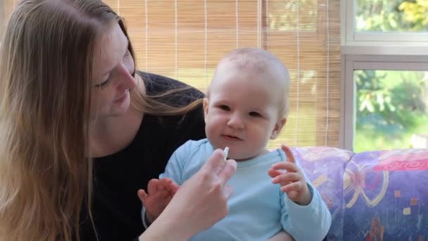 Mother at baby care giving her baby a nasal spray for colds - Footage, Video