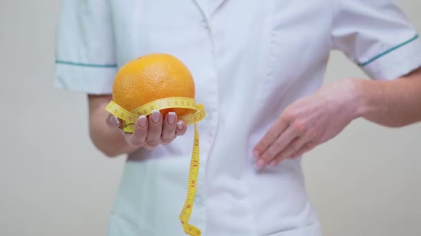 nutritionist doctor healthy lifestyle concept - holding orange fruit and measuring tape - Záběry, video