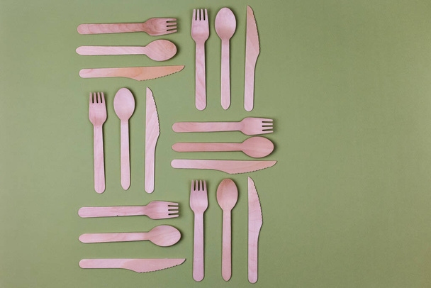 Wooden spoons, forks, knives on a green background. Pattern. Zero waste concept. - Photo, Image