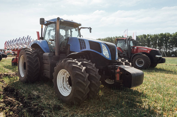 el tractor grande azul con las ruedas grandes en el campo en verano
 - Foto, imagen