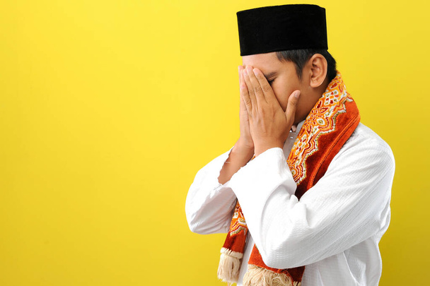 Młody muzułmanin azjatycki smuci się zakrywając twarz rękami. Koncepcja przestrzeni kopiującej, izolowana na żółtym tle - Zdjęcie, obraz