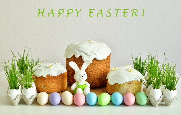 Easter orthodox sweet bread,multicolored eggs with green grass.Easter greeting card template.Text HAPPY EASTER.Easter sweets on light background.Holidays breakfast concept. copy space.Selective focus - Photo, Image