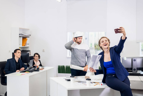 Les employés s'amusent au bureau, posent et prennent des selfies avec un smartphone - Photo, image