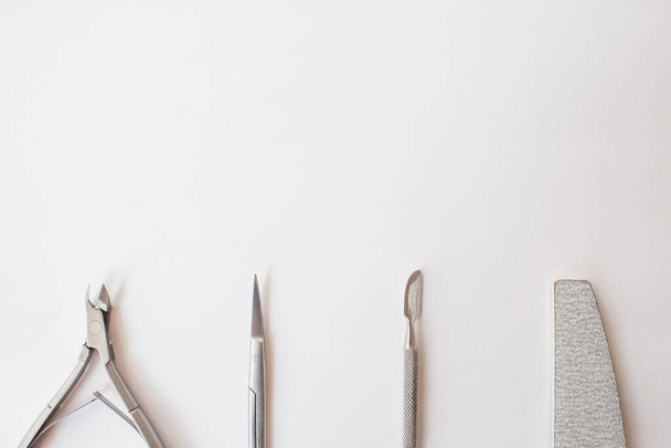  manicure set on a white background: scissors, pusher, nail file, tongs. professional pedicure tool - Фото, изображение