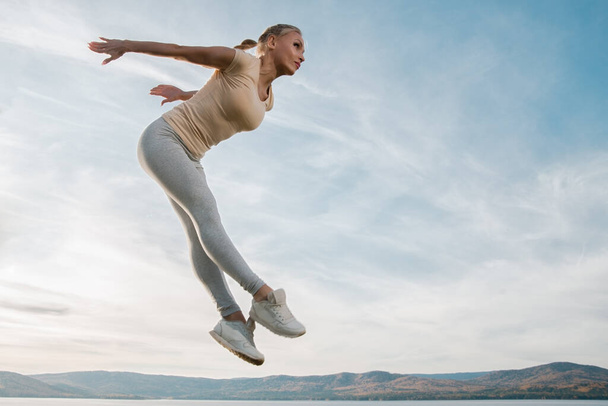 piękna kobieta fitness instruktor skacze na tle nieba - Zdjęcie, obraz